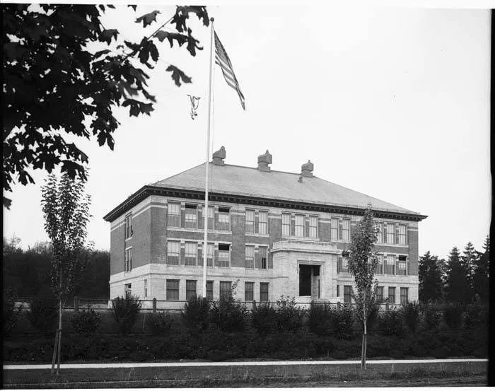 Historic black-and-white photograph of McGilvra School in 1915, with its flagpole and young trees